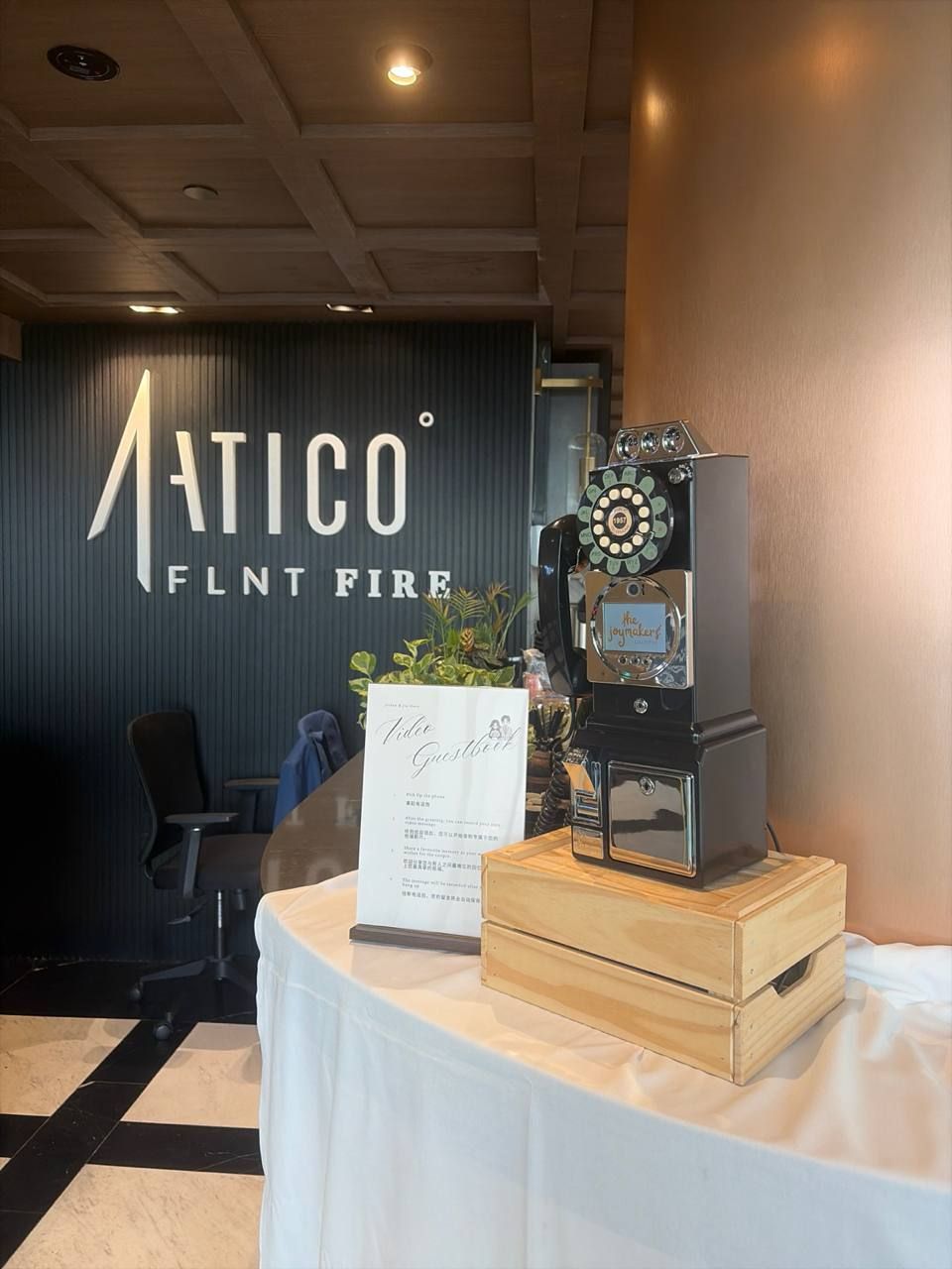 A black retro payphone guestbook on a wooden crate at a restaurant event, with a guestbook sign